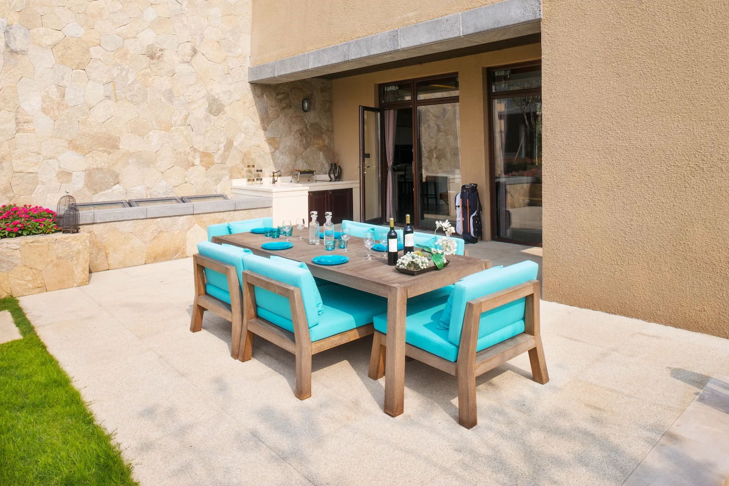 Concrete patio with an outdoor dining setting beside a sandstone wall