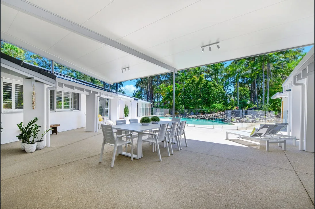 Covered concrete entertaining area opening onto a pool surround